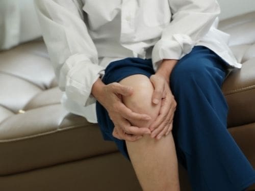 Molti sono i fattori che possono generare l'artrite reumatoide: scopri quali sono le cause principali! Donna si tiene il ginocchio a causa di un dolore