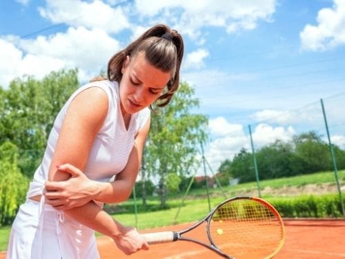 Ragazza gioca a tennis e si mantiene il gomito