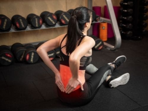La giusta prevenzione può evitare l'insorgere dell'ernia del disco: scopri come fare! Donna dolorante alla schiena mentre si allena