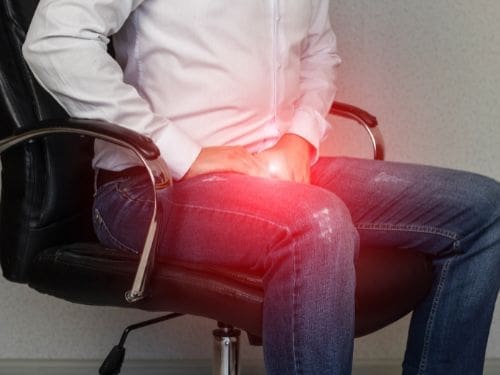 Uomo seduto dolorante a causa della malattia di Peyronie