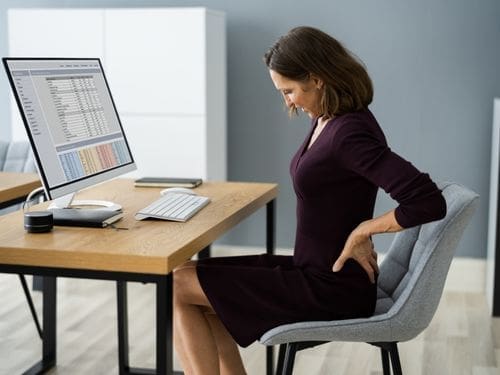 Scopri quali sono i principali sintomi causati dalla lombalgia! Donna si tocca la schiena a causa di un dolore